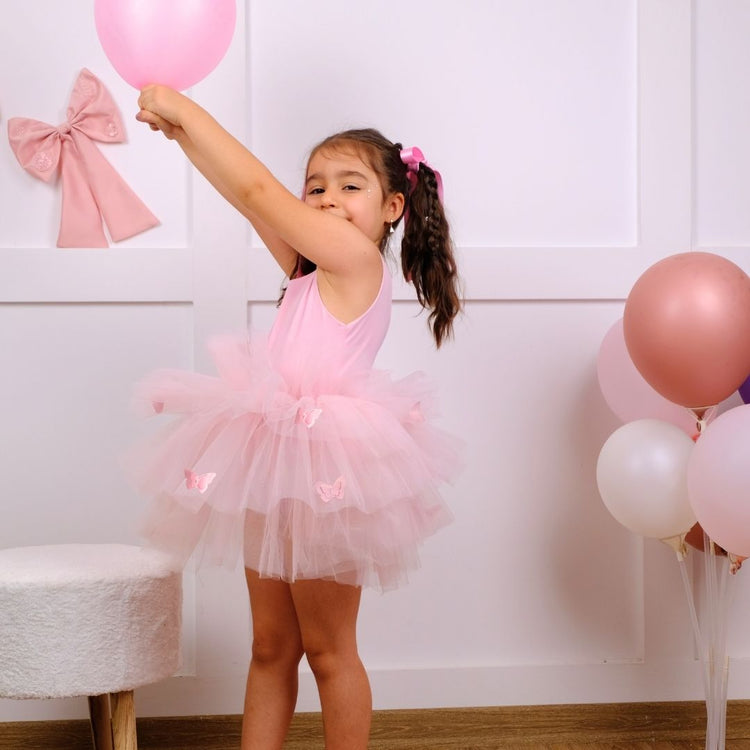 a little girl in a pink tutu holding a pink balloon