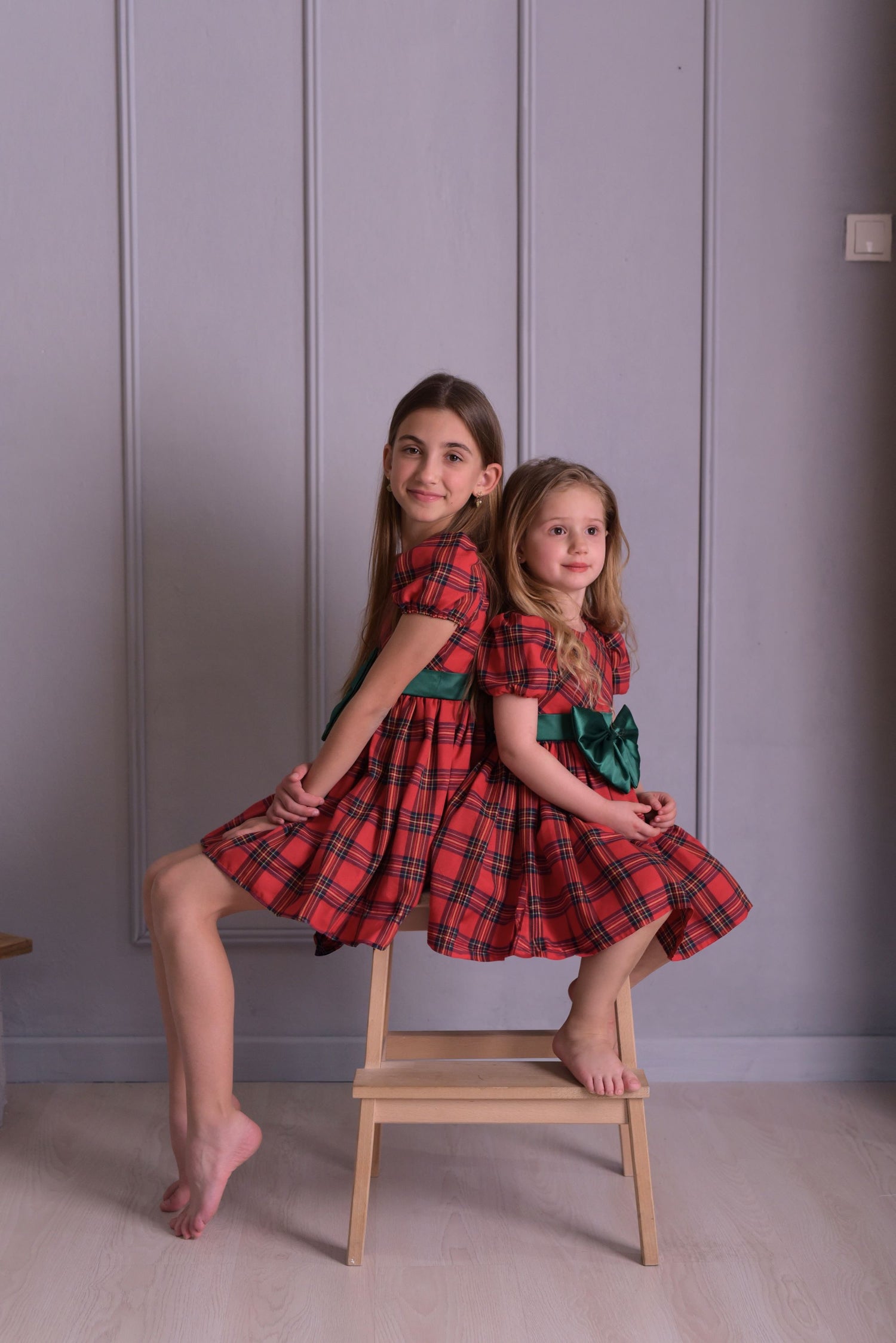 two little girls sitting on a chair posing for a picture