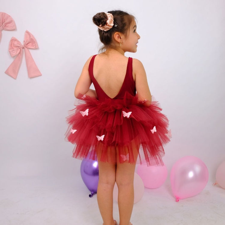 a little girl in a red dress standing in front of balloons