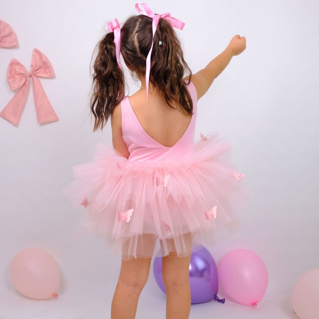 a little girl wearing a pink tutu and a pink bow