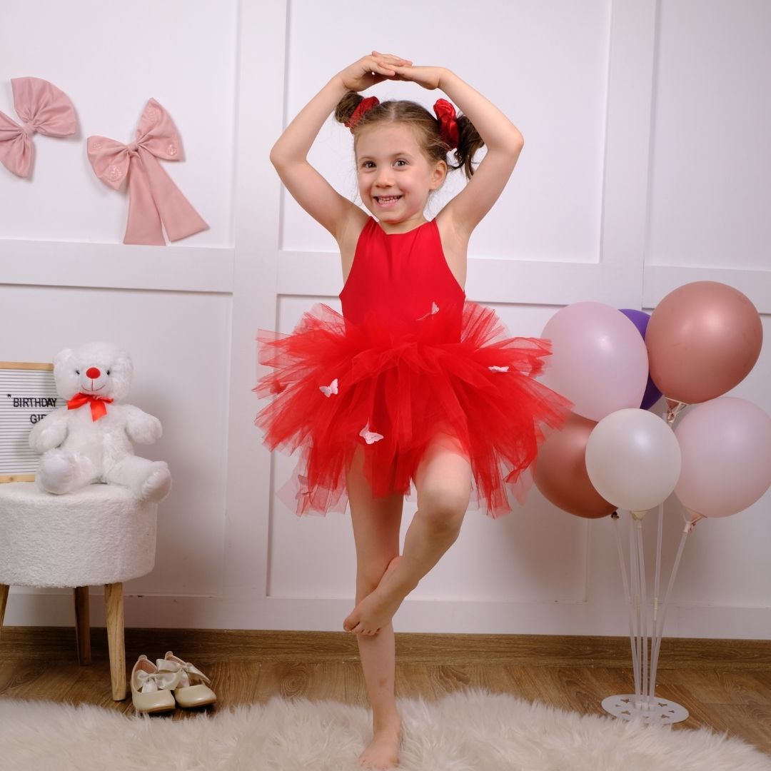 a little girl in a red tutu is posing for a picture