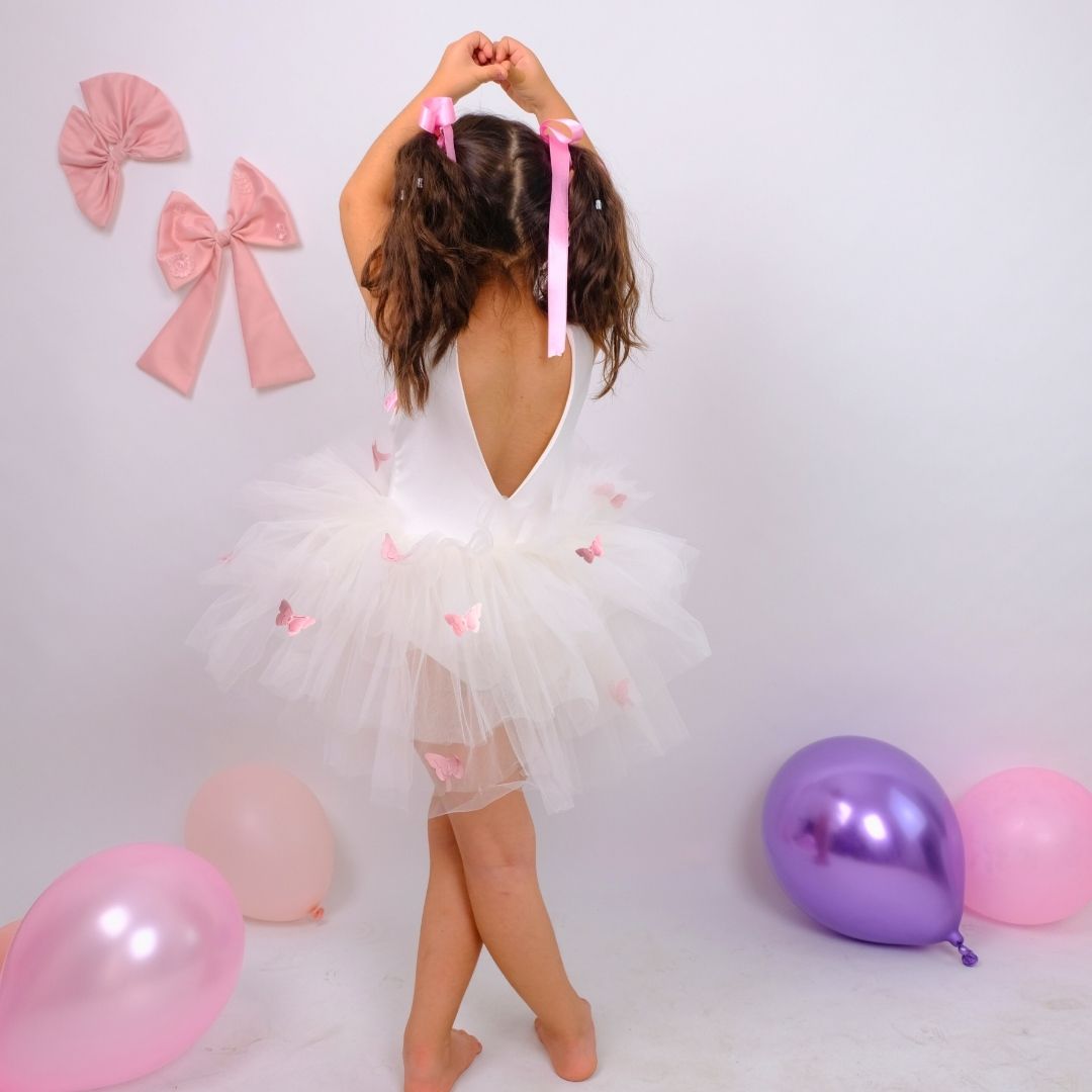 a little girl in a white dress standing in front of balloons