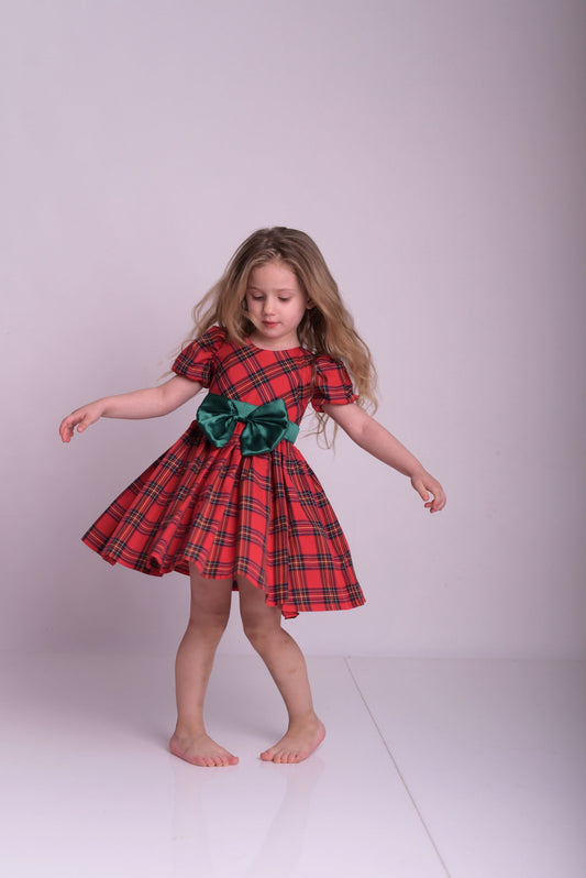 a little girl in a red and green dress