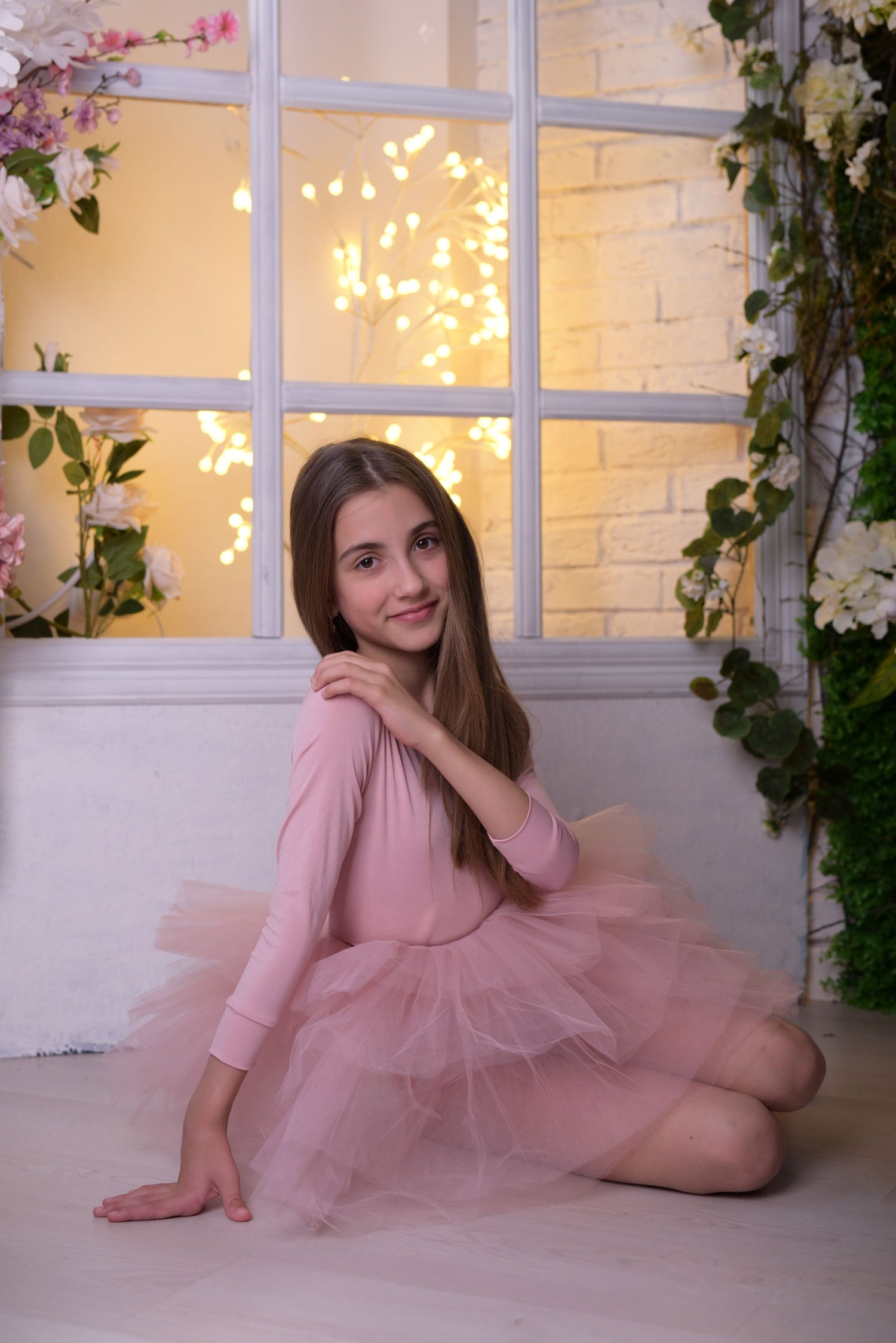 a girl in a pink dress sitting on the floor