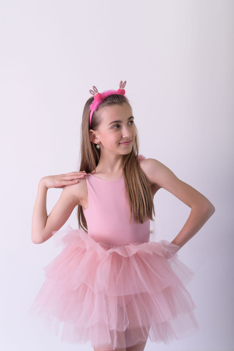 a little girl in a pink dress posing for a picture