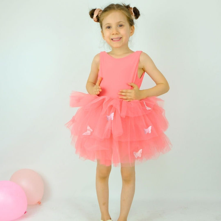 a little girl in a pink dress standing next to balloons