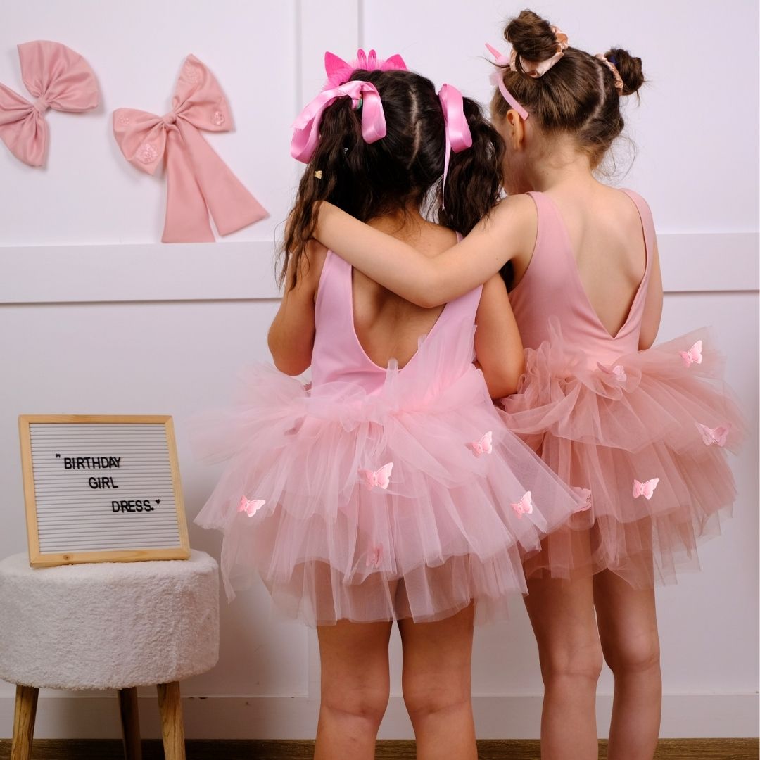 two little girls dressed in pink tutu skirts