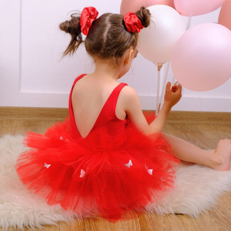 a little girl sitting on the floor with balloons