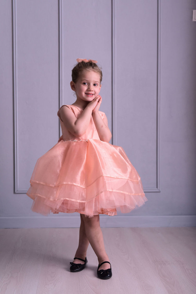 a little girl in a pink dress posing for a picture