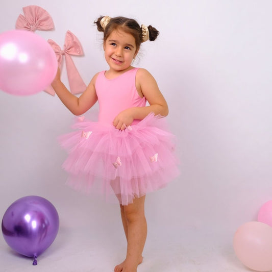 a little girl in a pink tutu holding a balloon