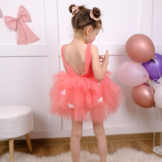 a little girl in a pink dress standing in front of balloons