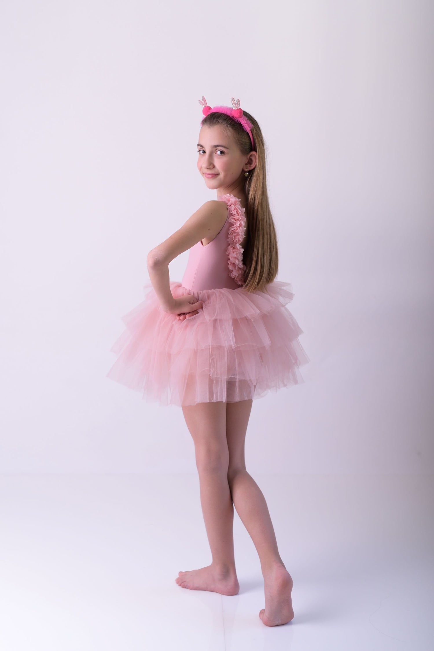 a little girl in a pink dress posing for a picture