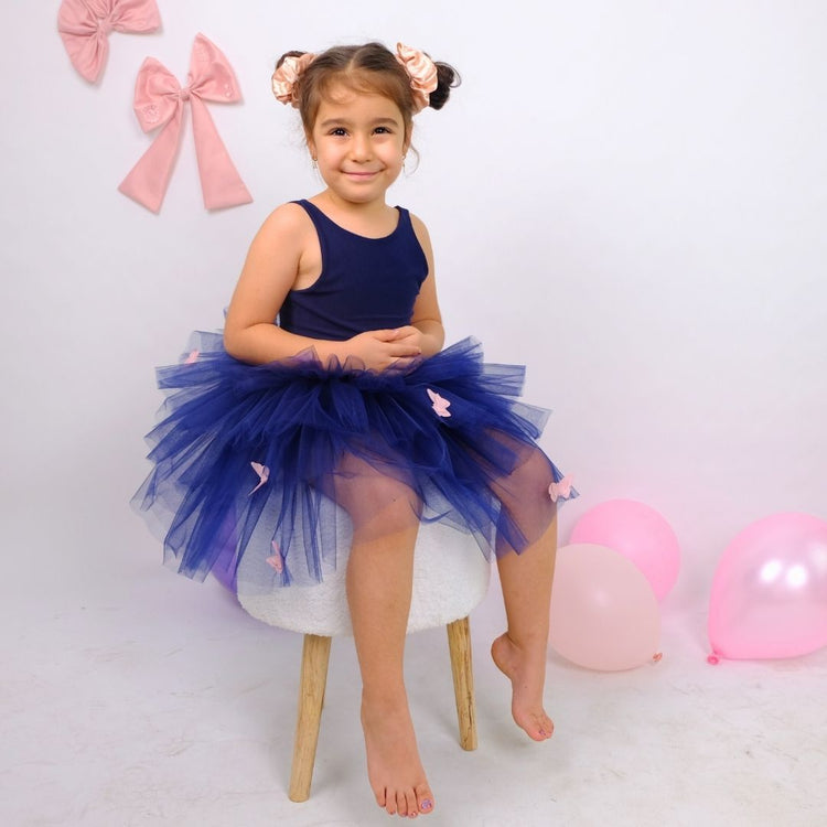 a little girl sitting on a chair in a blue dress