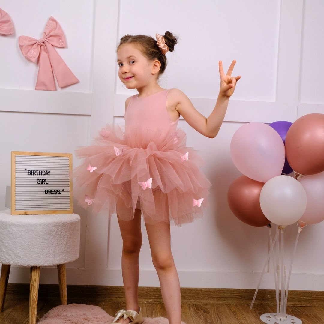 a little girl in a pink dress posing for a picture