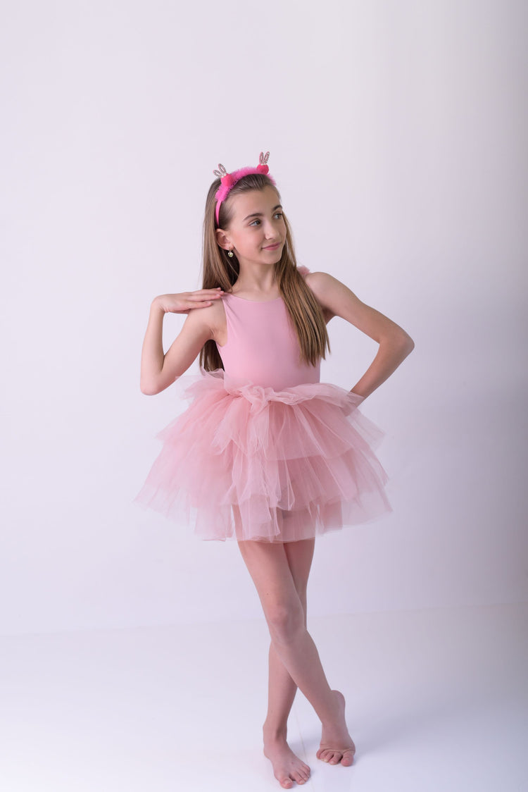 a little girl in a pink dress posing for a picture