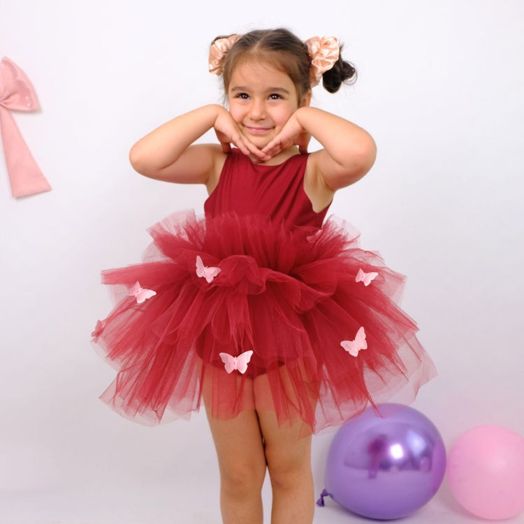 a little girl in a red dress standing next to balloons