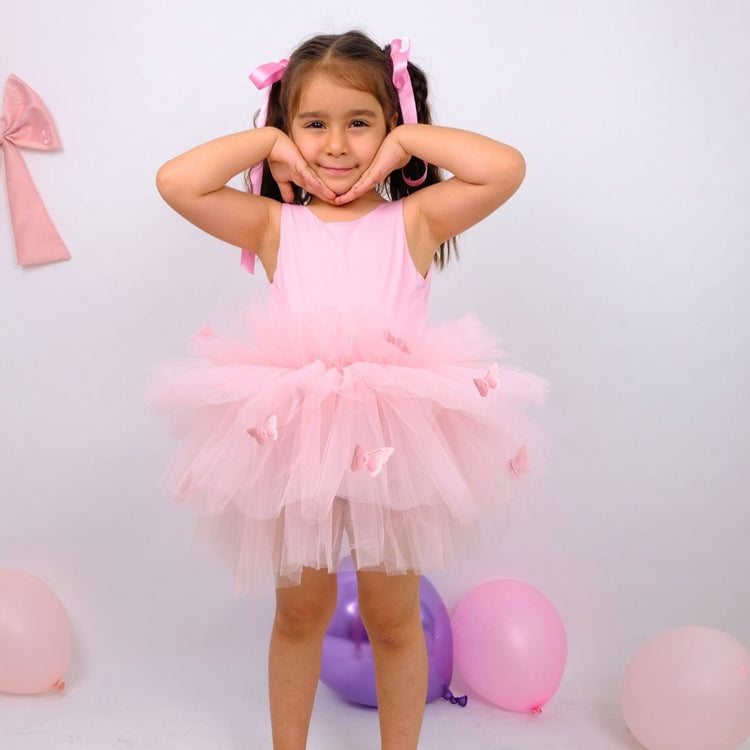 a little girl in a pink dress posing for a picture