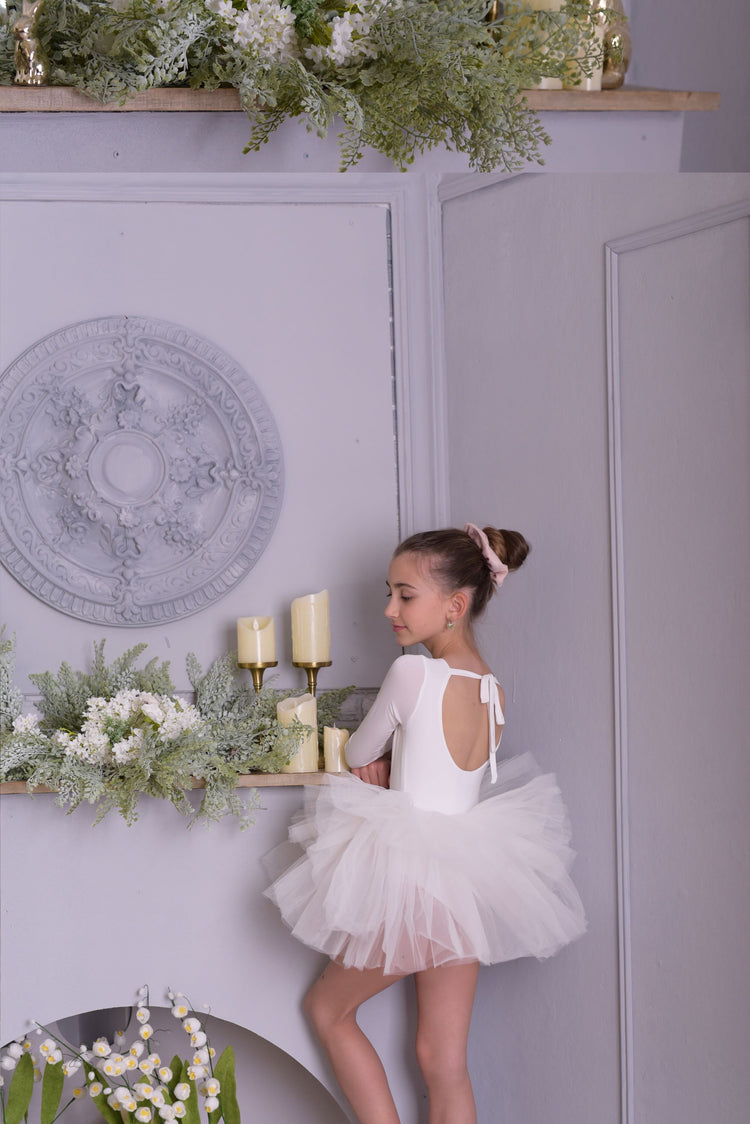 a little girl in a white dress standing on a shelf