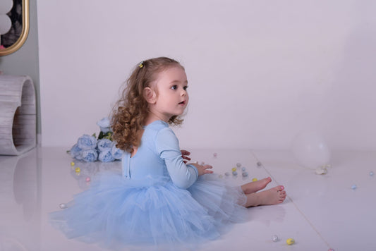 a little girl in a blue dress sitting on the floor