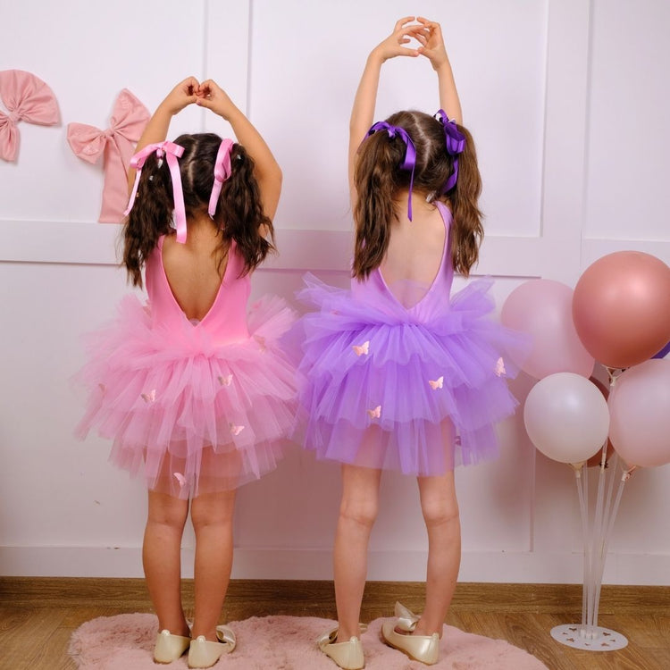 two little girls dressed in pink and purple tutus