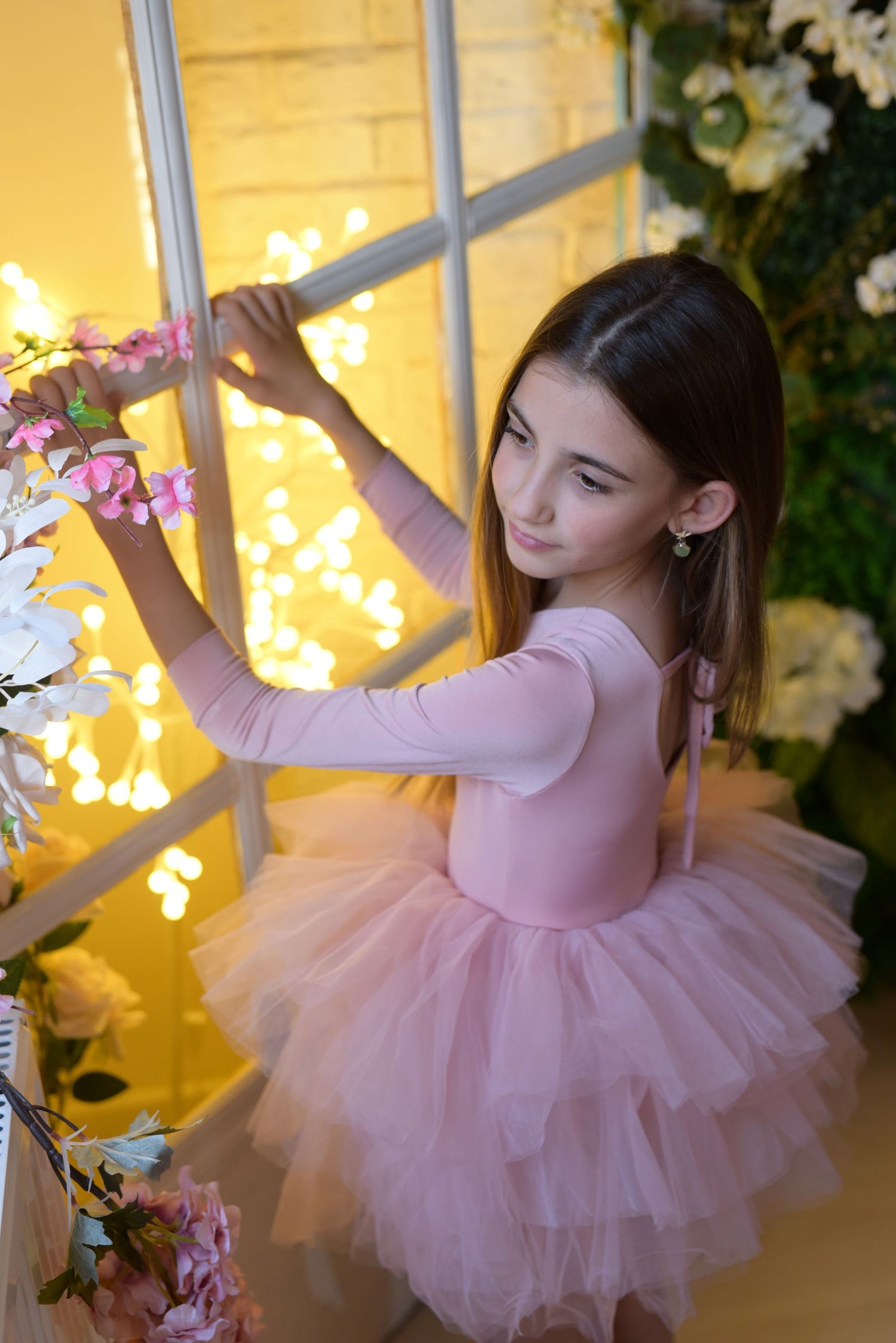 a little girl in a pink tutu holding flowers