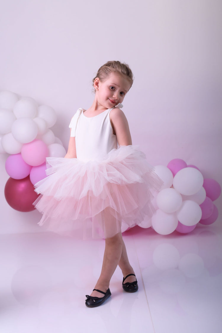 a little girl wearing a pink tutu and a white dress