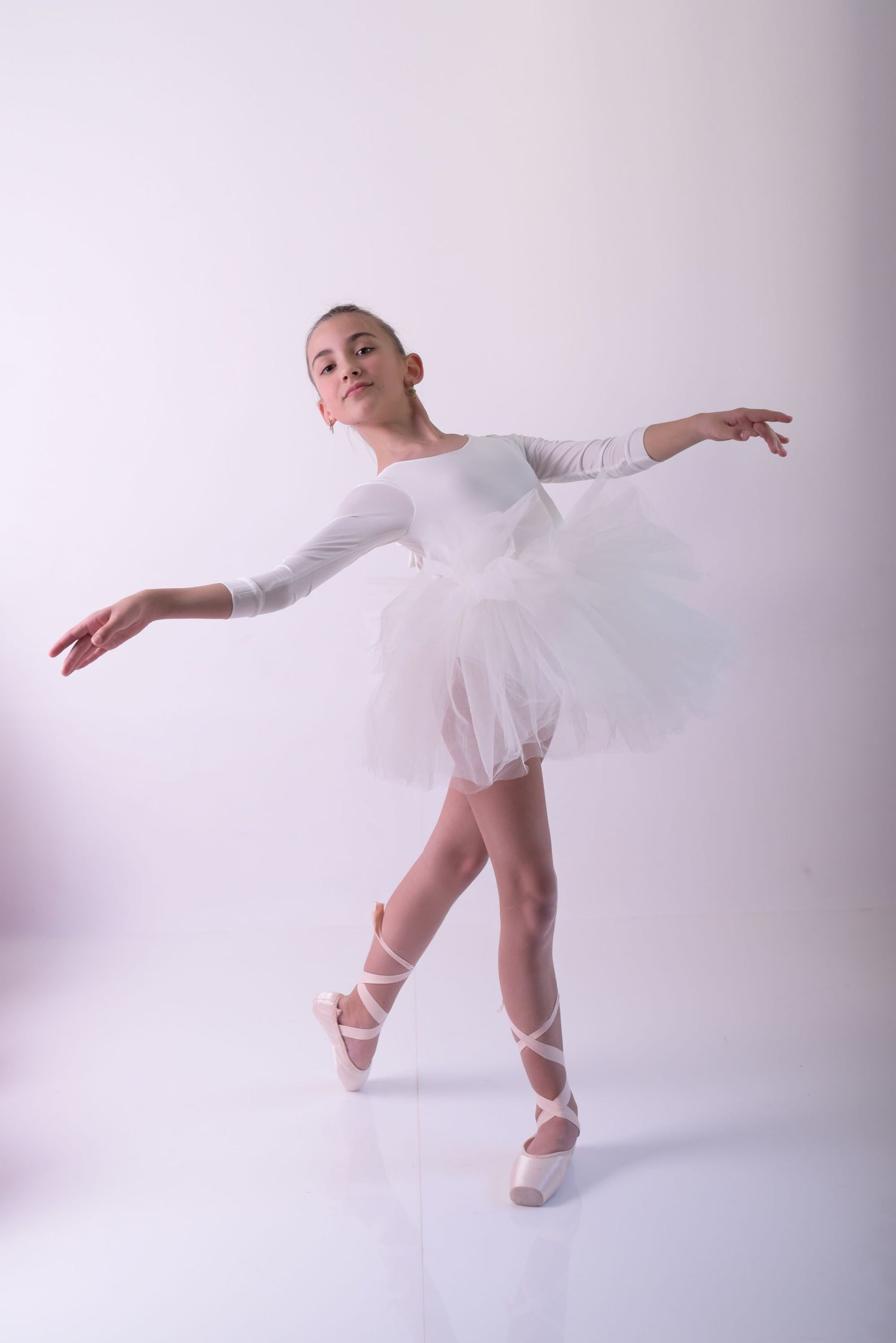 a young ballerina in a white tutu and ballet shoes