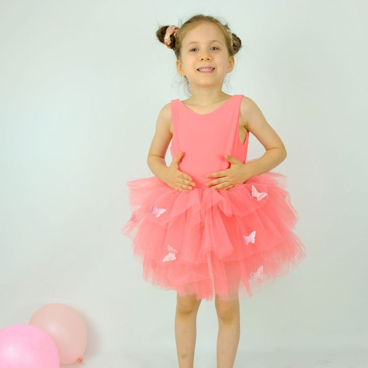 a little girl in a pink dress standing next to balloons