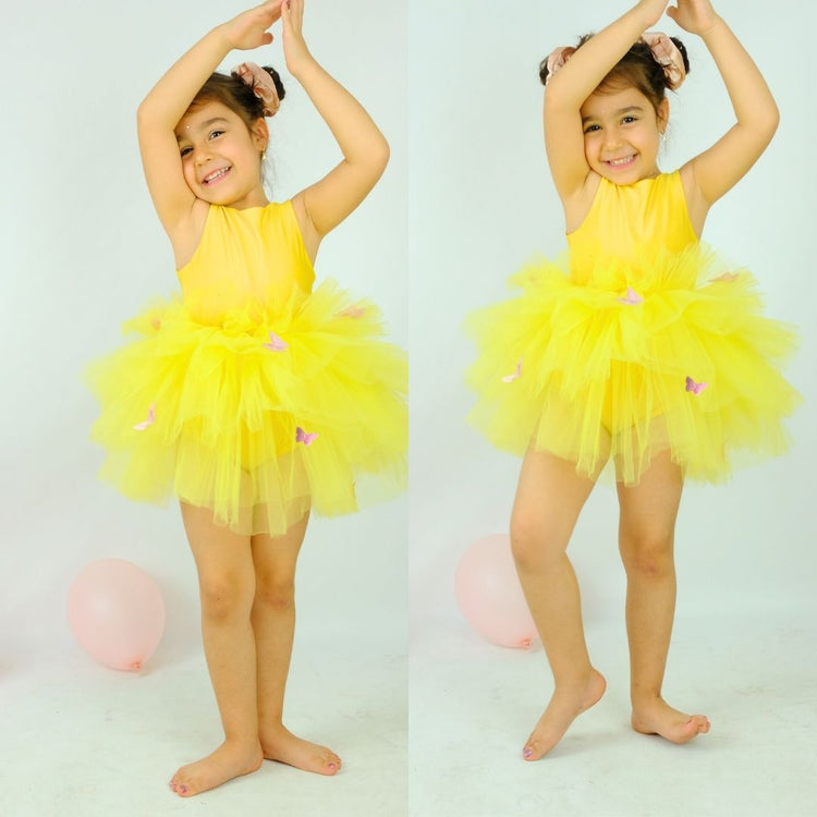 a little girl wearing a yellow tutu and a yellow dress