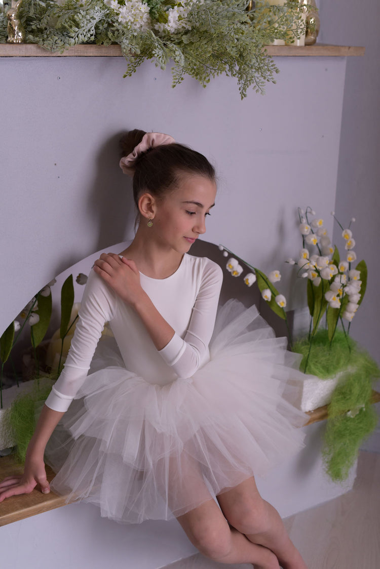 a young girl sitting on a chair wearing a tutu