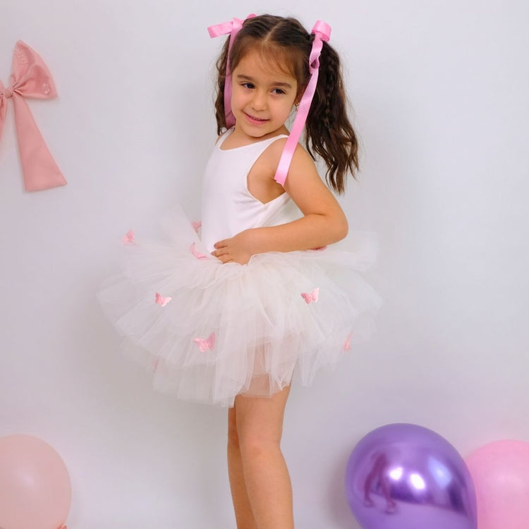 a little girl in a tutu and a pink bow