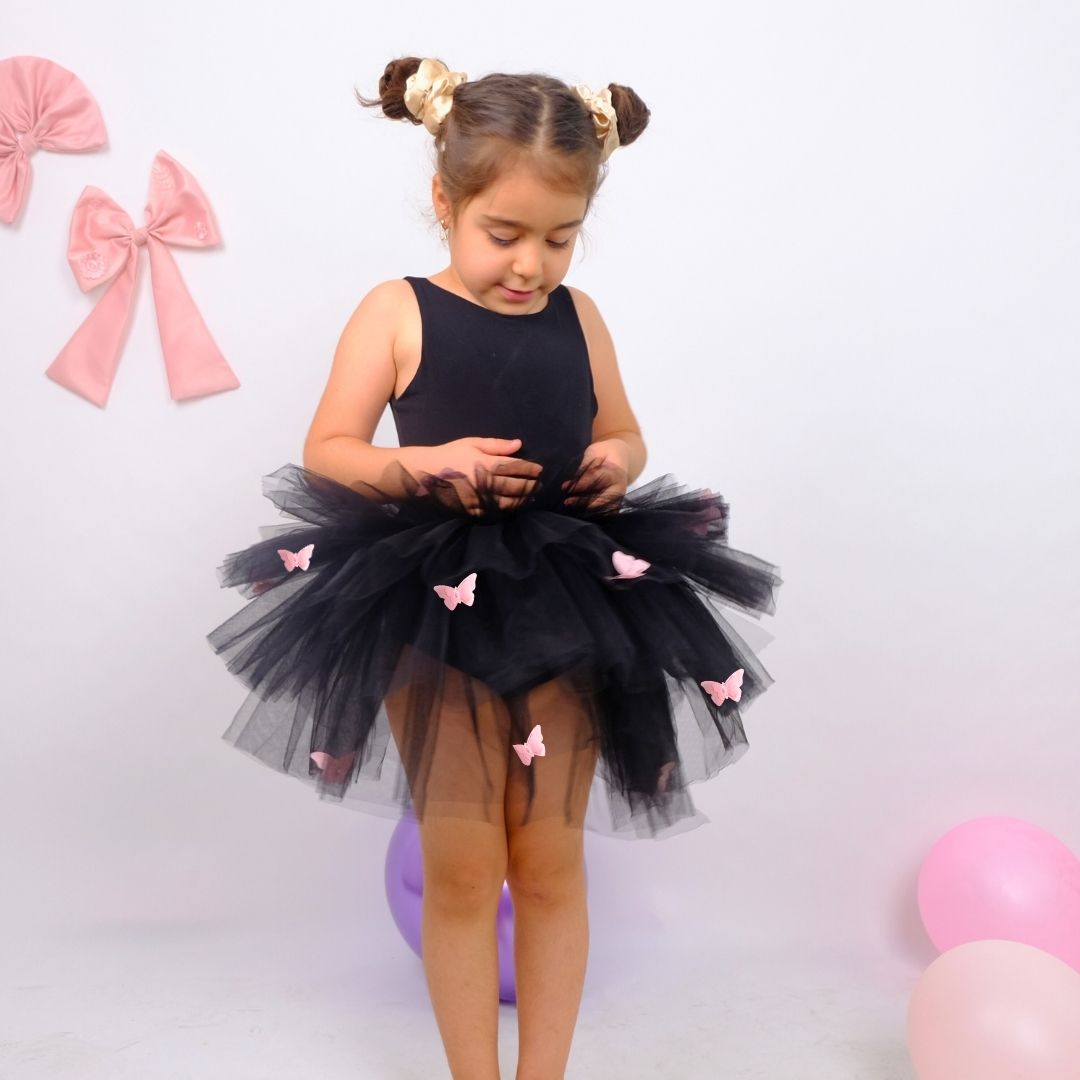 a little girl wearing a black dress with pink butterflies on it