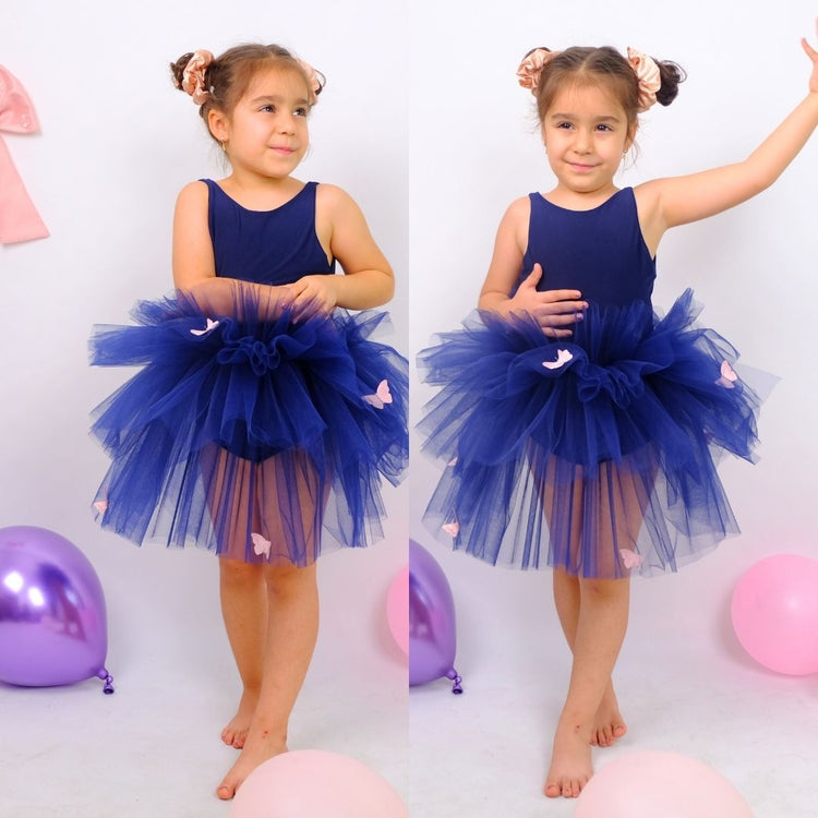 two little girls in blue dresses standing next to balloons