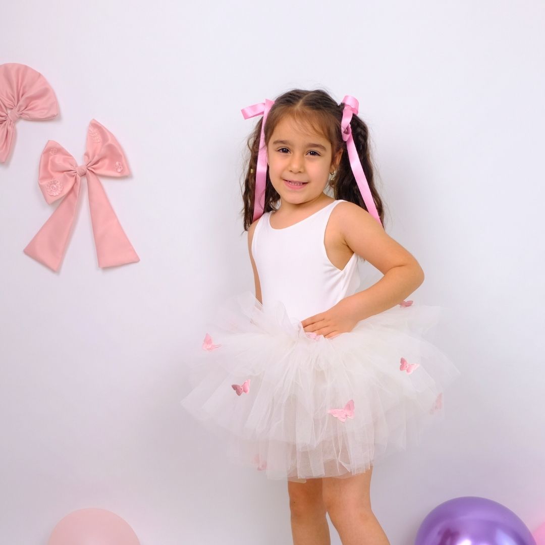 a little girl wearing a white dress and a pink bow