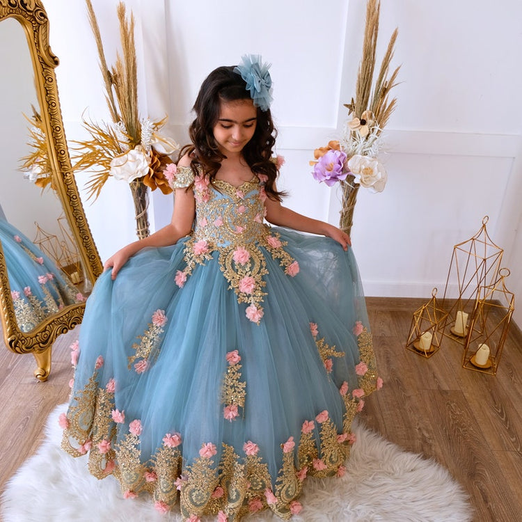 The bodice of the light pastel blue dress is laced and has laser flowers on it. The whole skirt is embroidered with lace and tulle on tulle.