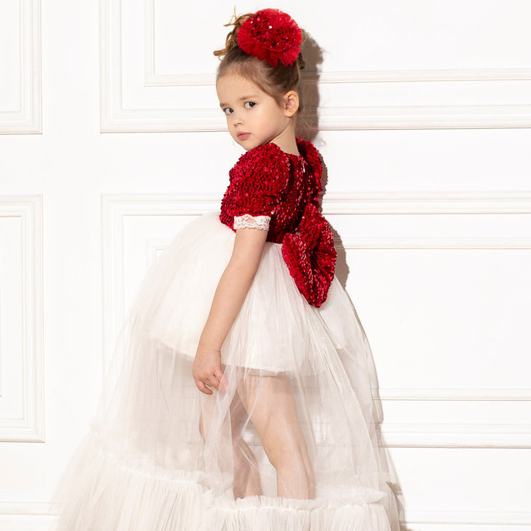 a little girl in a white dress with a red teddy bear