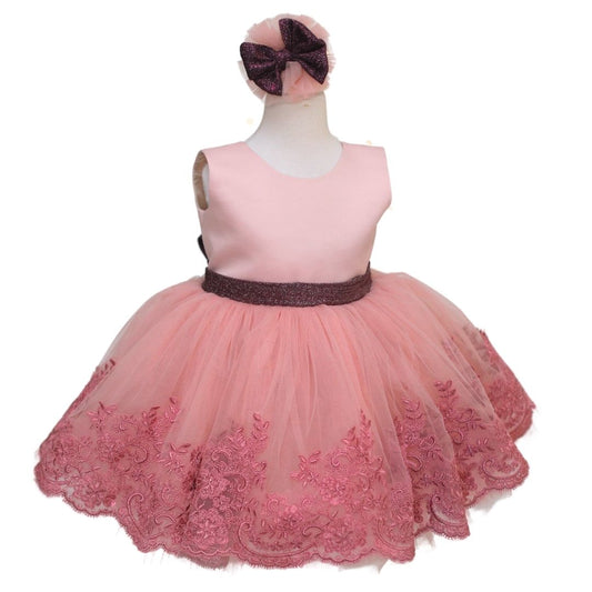 a little girl wearing a pink dress with a bow