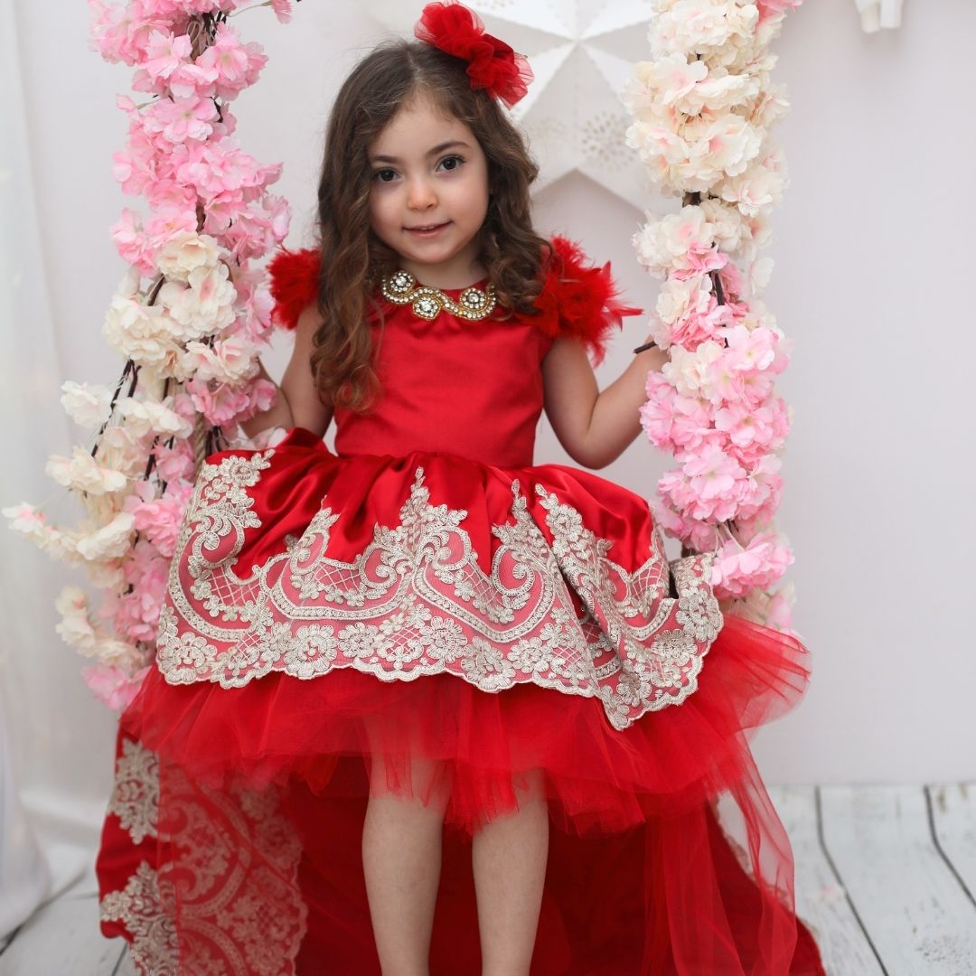 a little girl in a red dress sitting on a swing