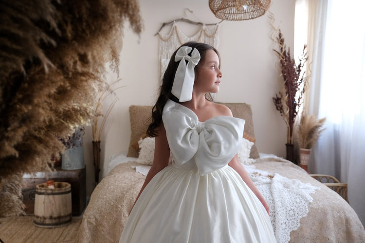 a woman in a white dress standing in front of a bed