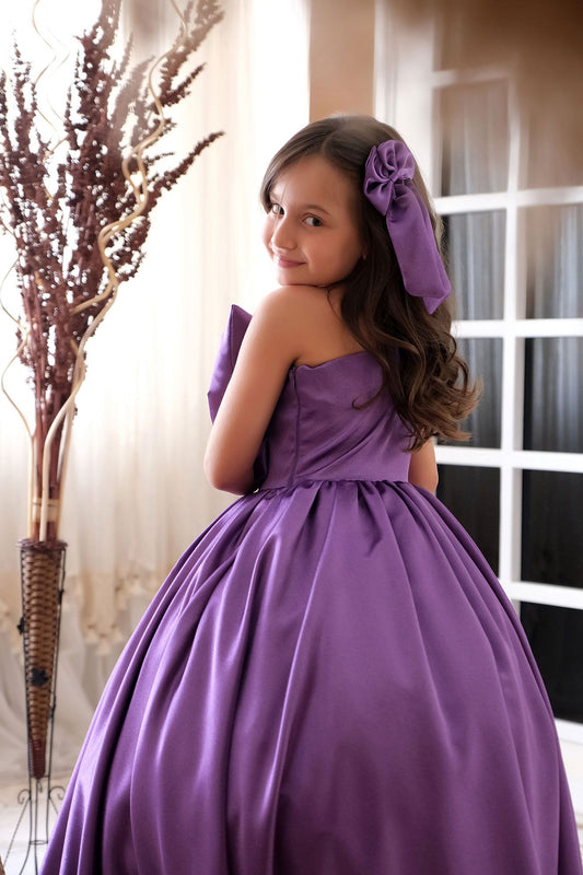 a little girl in a purple dress posing for a picture