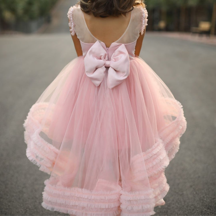 a little girl wearing a pink dress with a big bow