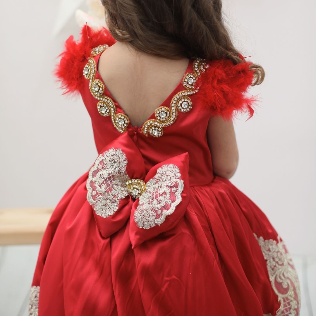 a little girl in a red dress with a red feather