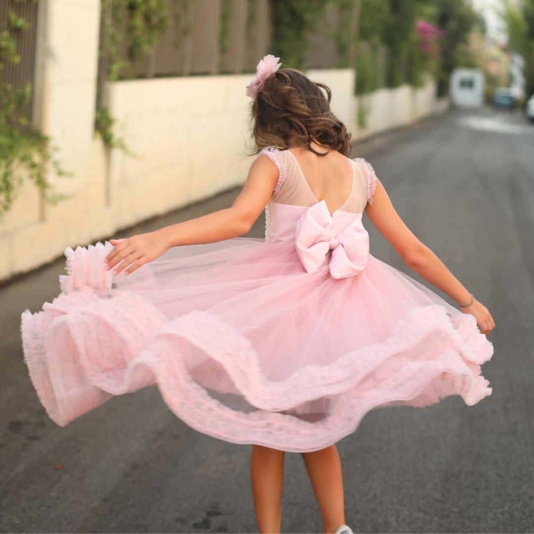 a little girl in a pink dress walking down the street