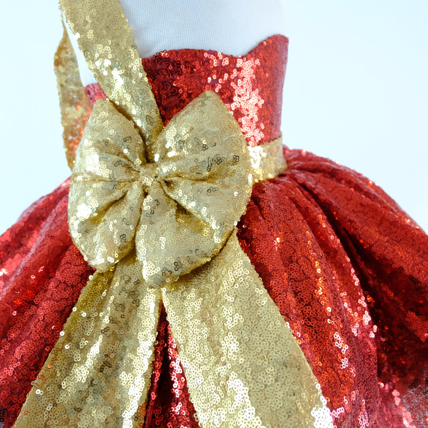 a red and gold dress with a big bow