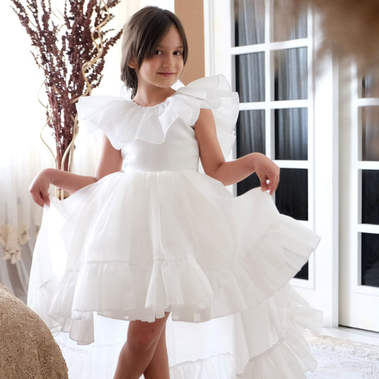 a little girl in a white dress standing in a room