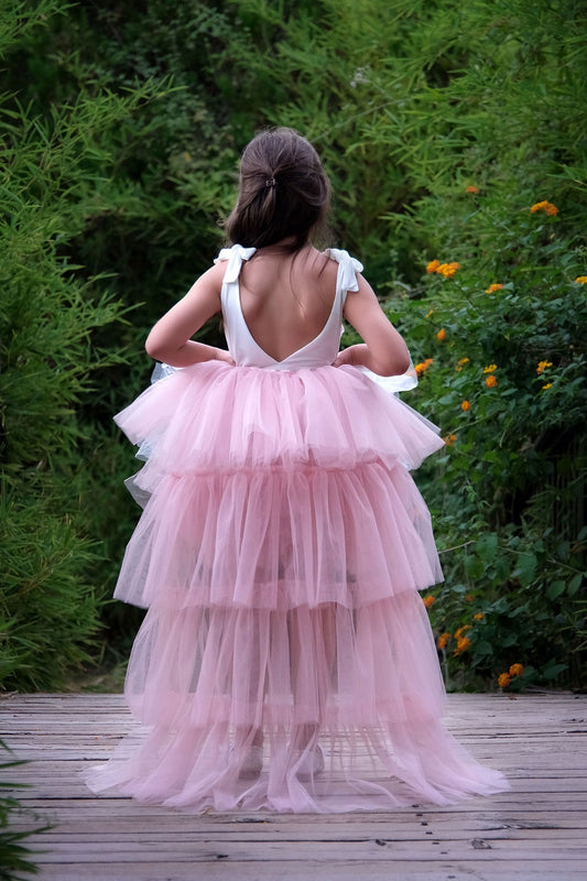 a little girl in a pink dress walking on a wooden walkway