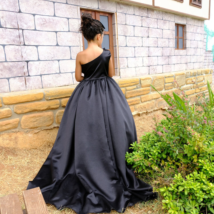 a woman in a black dress standing in front of a brick building