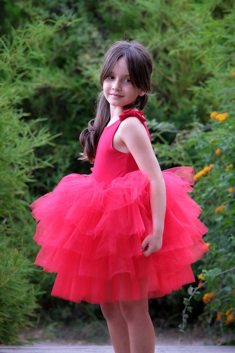 a little girl in a red dress posing for a picture
