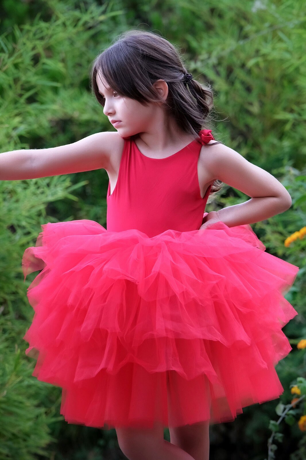 a little girl in a red dress standing in a field