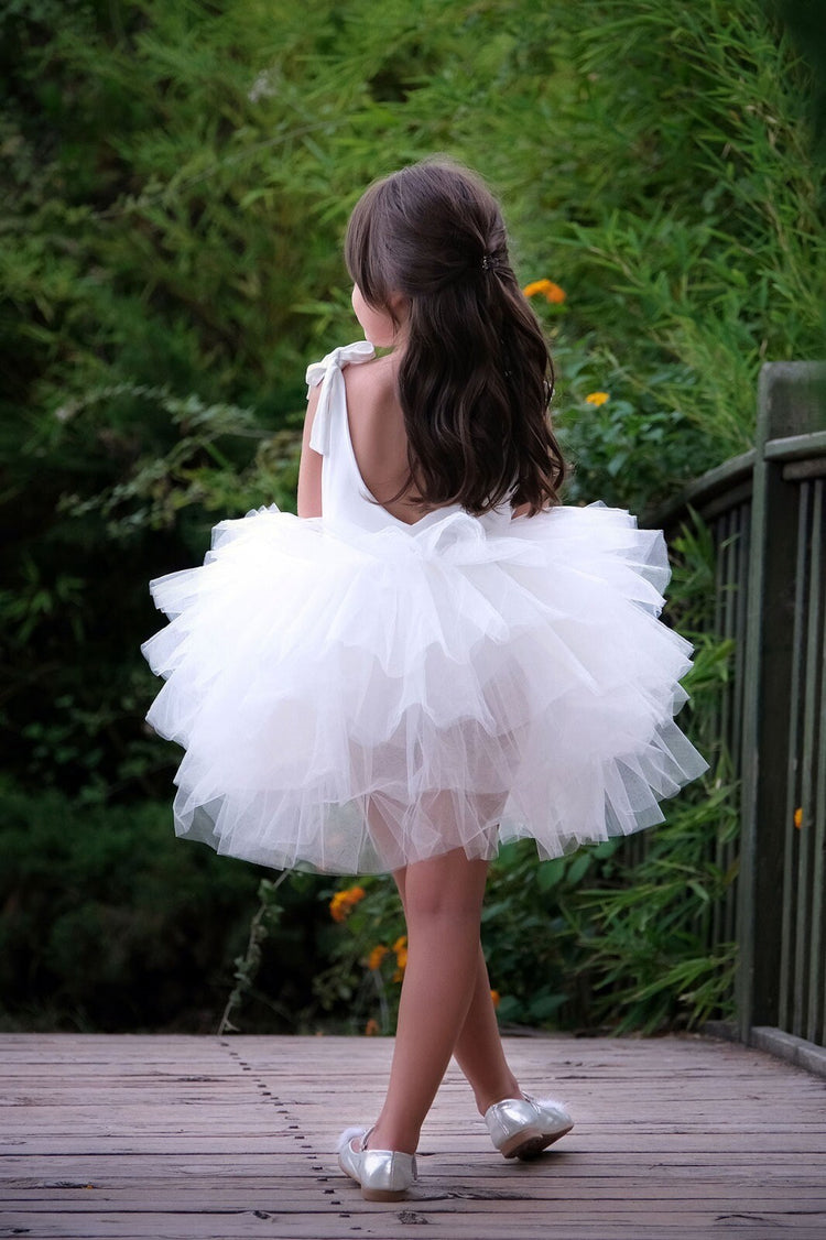 a little girl wearing a white dress and silver shoes